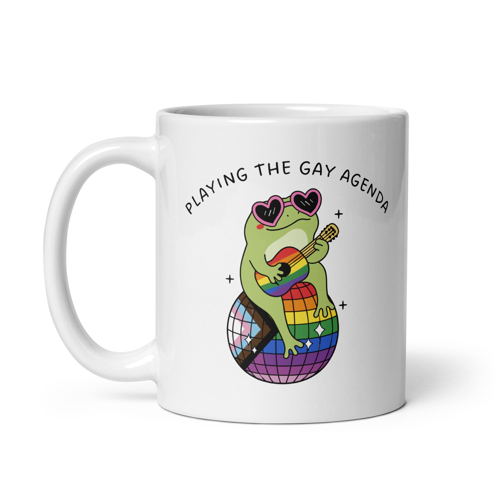 White ceramic mug displaying a colorful disco frog illustration, rainbow disco ball, and playful “Playing the Gay Agenda” LGBTQ+ pride design.