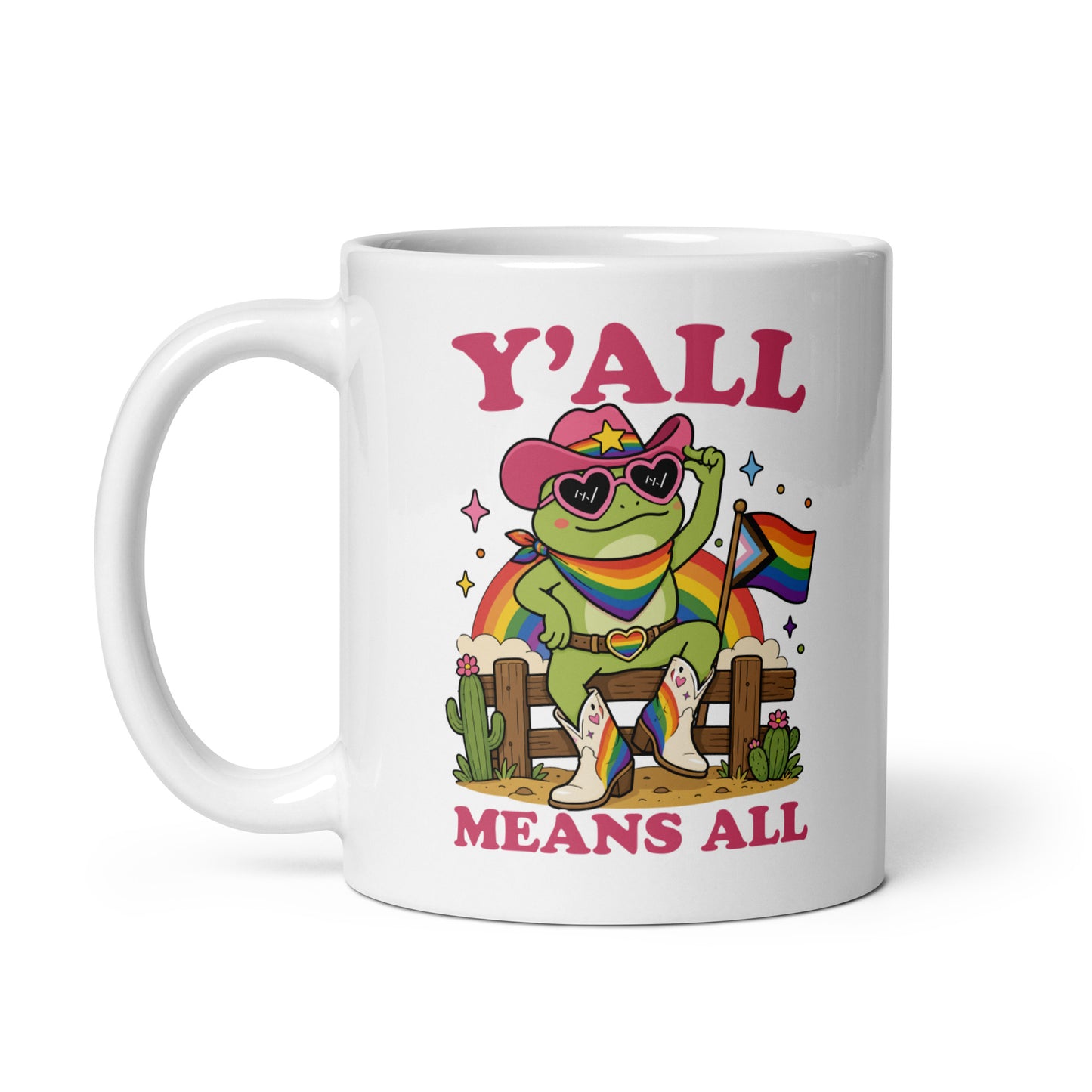 White ceramic mug displaying colorful cowboy frog artwork, rainbow pride flag details, and inclusive “Y’All Means All” message celebrating LGBTQ+ pride and belonging.