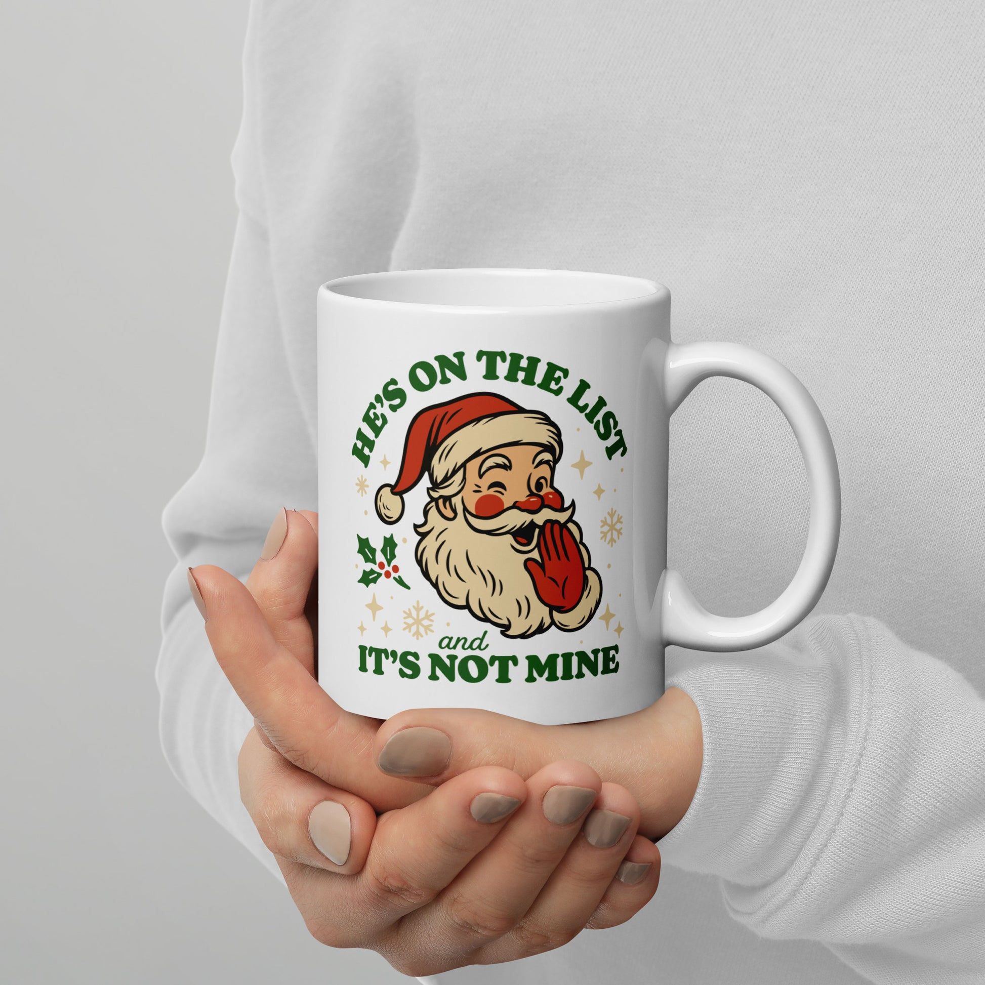 A person holding a white Christmas mug with the playful vintage Santa illustration and humorous “He’s On the List & It’s Not Mine” holiday message. A fun seasonal piece from Blue Wave USA.