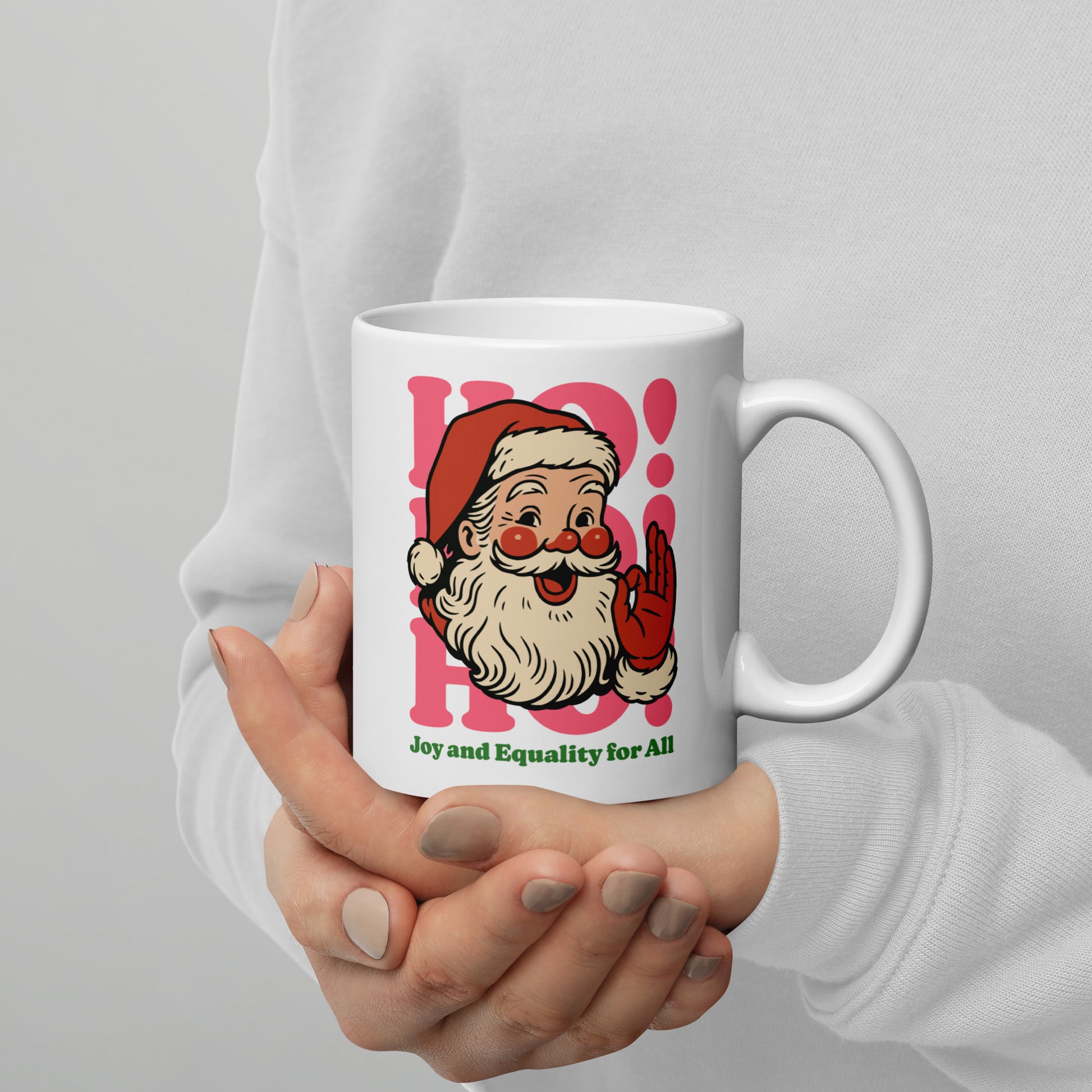 11 oz white mug with the vintage Santa design and “Joy and Equality for All” is held gently in both hands—progressive holiday style from Blue Wave USA.