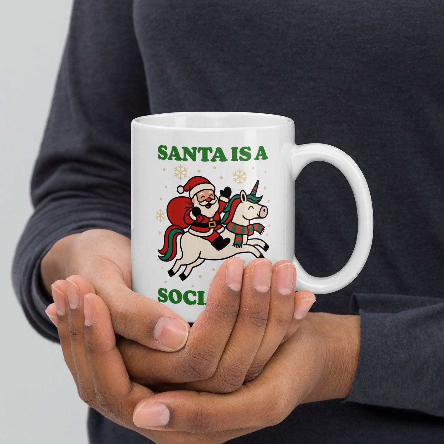 White 11 oz ceramic mug shown in one hand, printed with a vintage Santa riding a unicorn illustration, decorative stars, and the message “SANTA IS A SOCIALIST,” from Blue Wave USA.