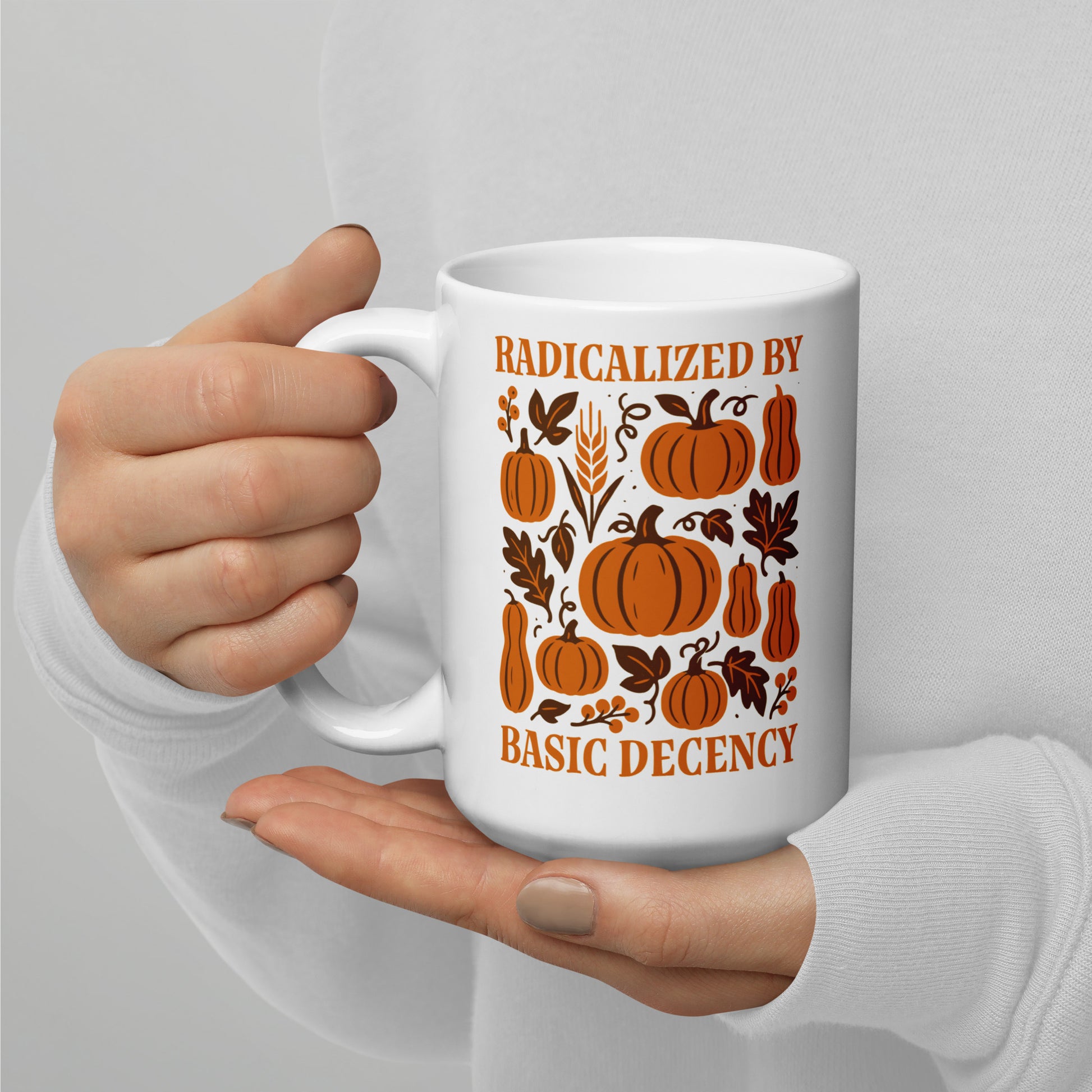 Activist mug with orange pumpkin pattern and “Radicalized by Basic Decency” message, autumn equality design for kind voters.