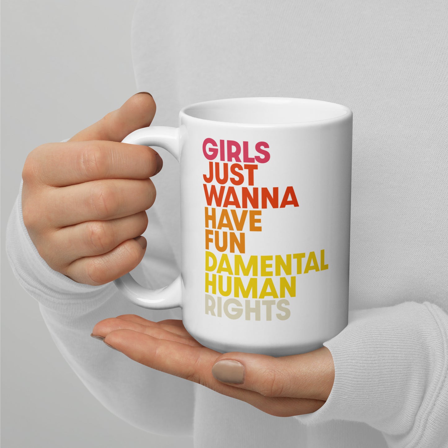 Close-up of “Girls Just Wanna Have Fundamental Human Rights” printed on a 15 oz white glossy mug, colorful text in pink, orange, and yellow.