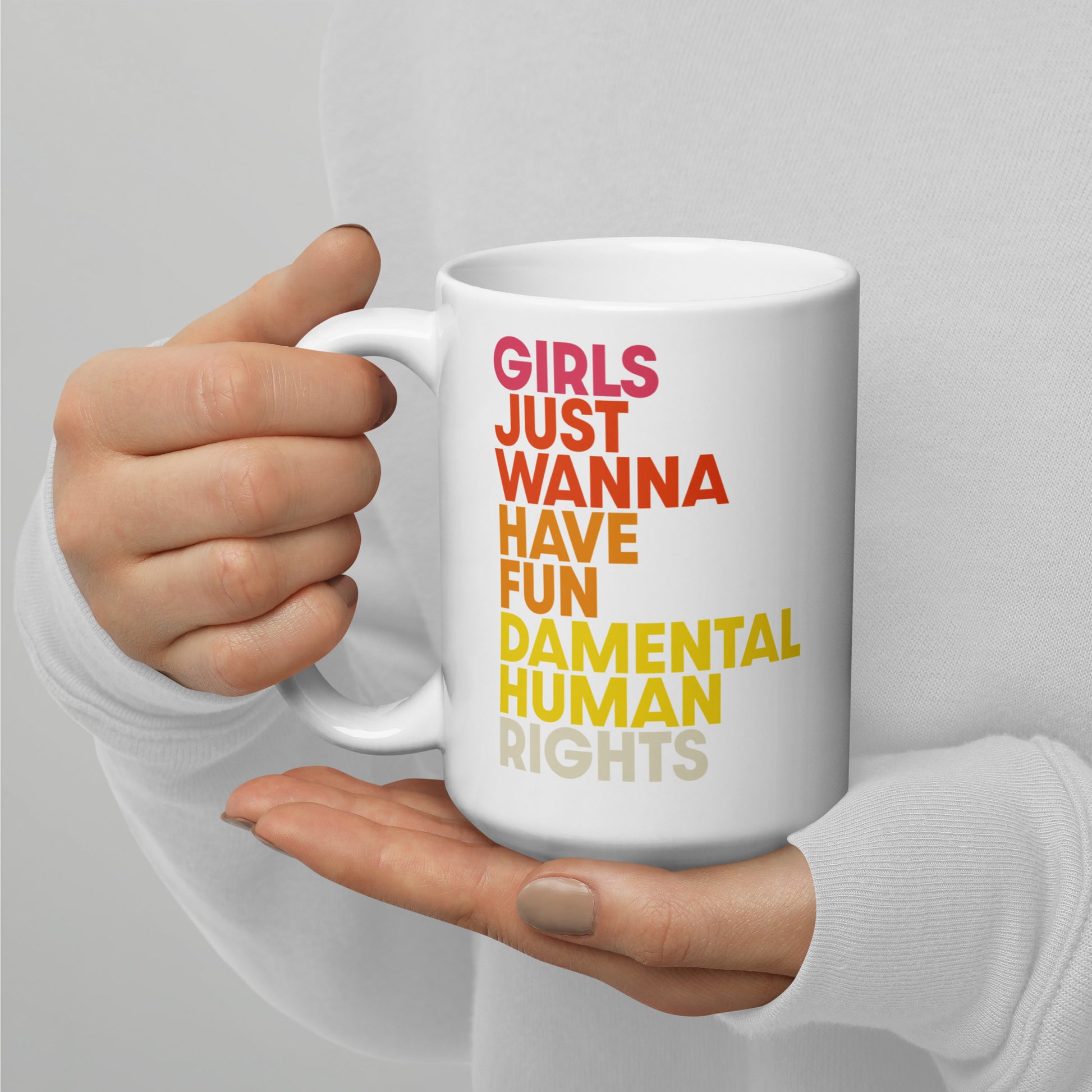Close-up of “Girls Just Wanna Have Fundamental Human Rights” printed on a 15 oz white glossy mug, colorful text in pink, orange, and yellow.