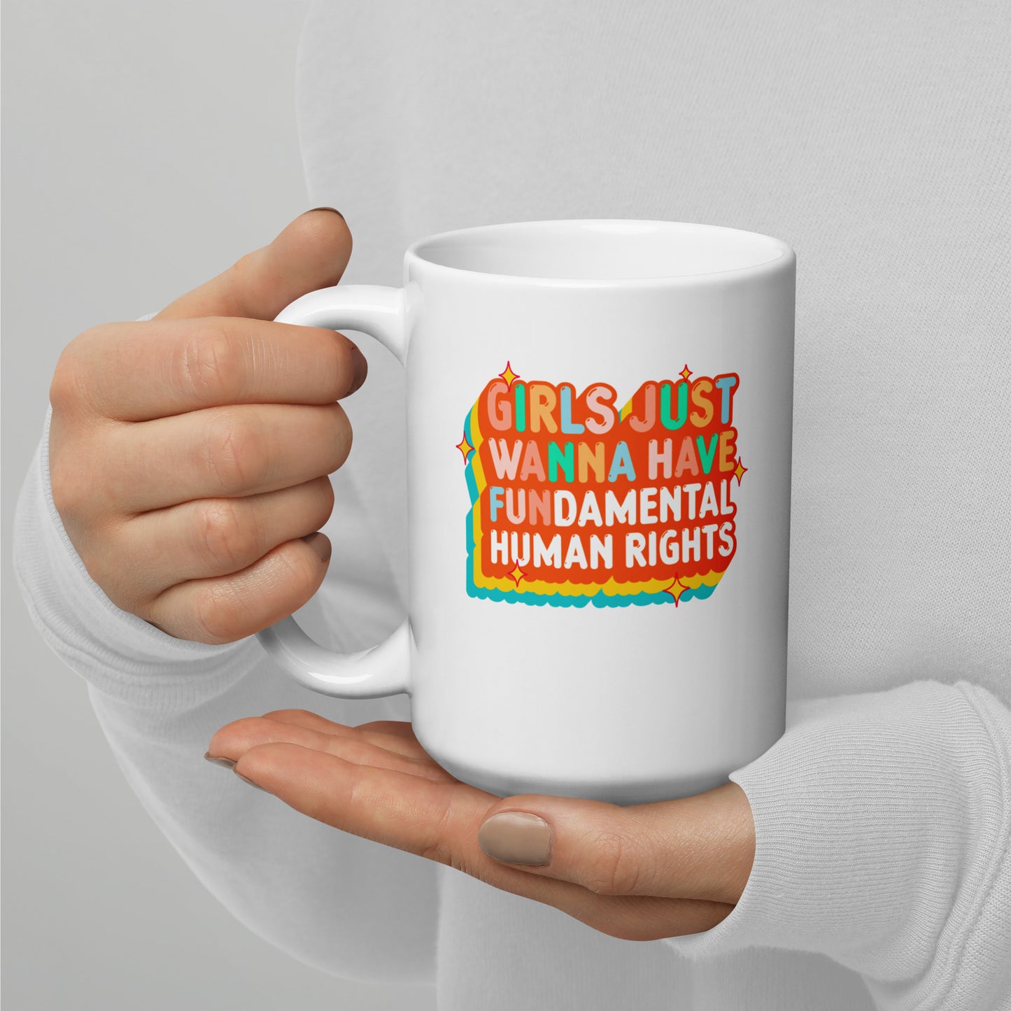 Activist coffee mug with layered orange and teal typography reading “Girls Just Wanna Have Fundamental Human Rights,” minimalist studio view.