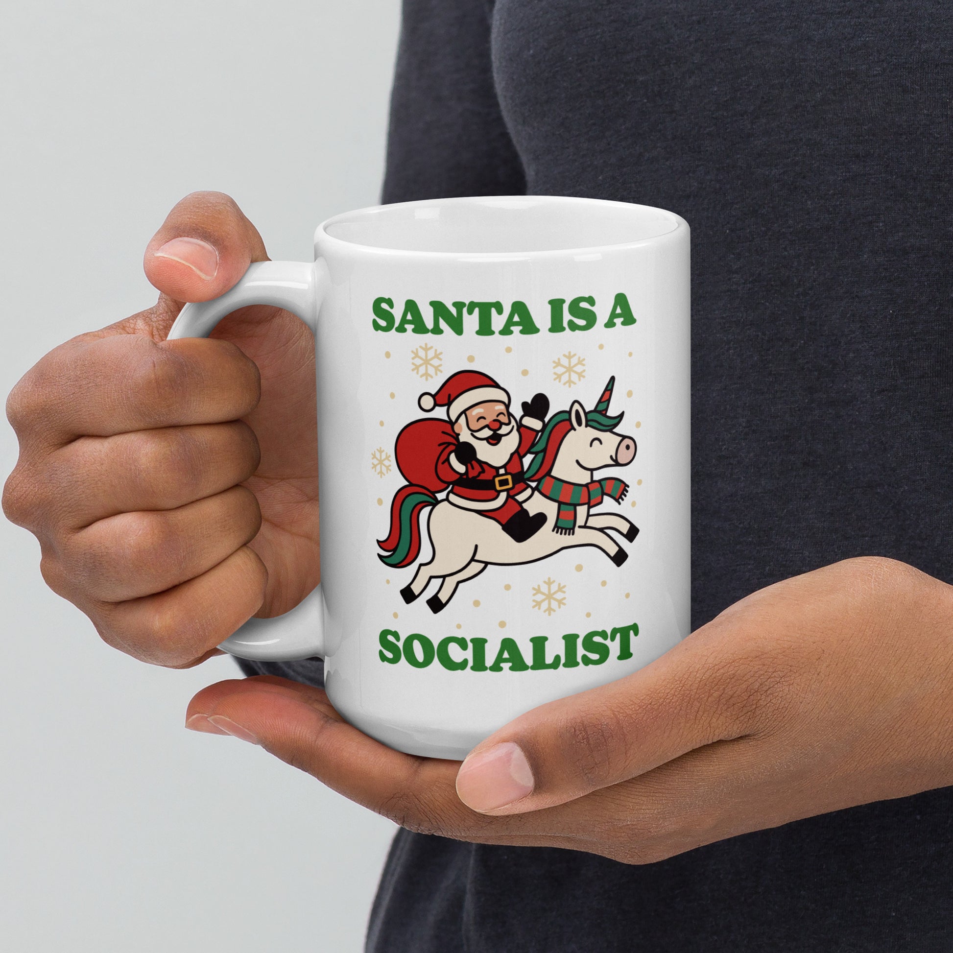White 15 oz ceramic mug held at an angle showing a vintage Santa riding a unicorn with stars and the printed message “SANTA IS A SOCIALIST,” designed by Blue Wave USA.
