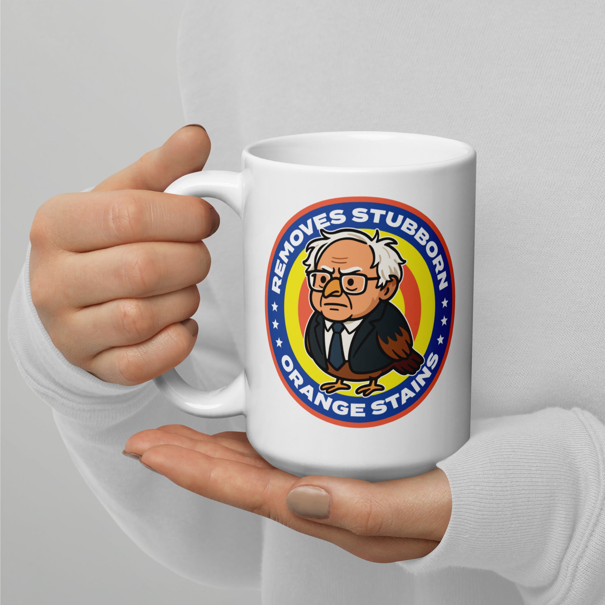 White coffee mug featuring Birdie Sanders spoof detergent badge and stubborn orange stains slogan, satirical political humor gift for desks and reading nooks.