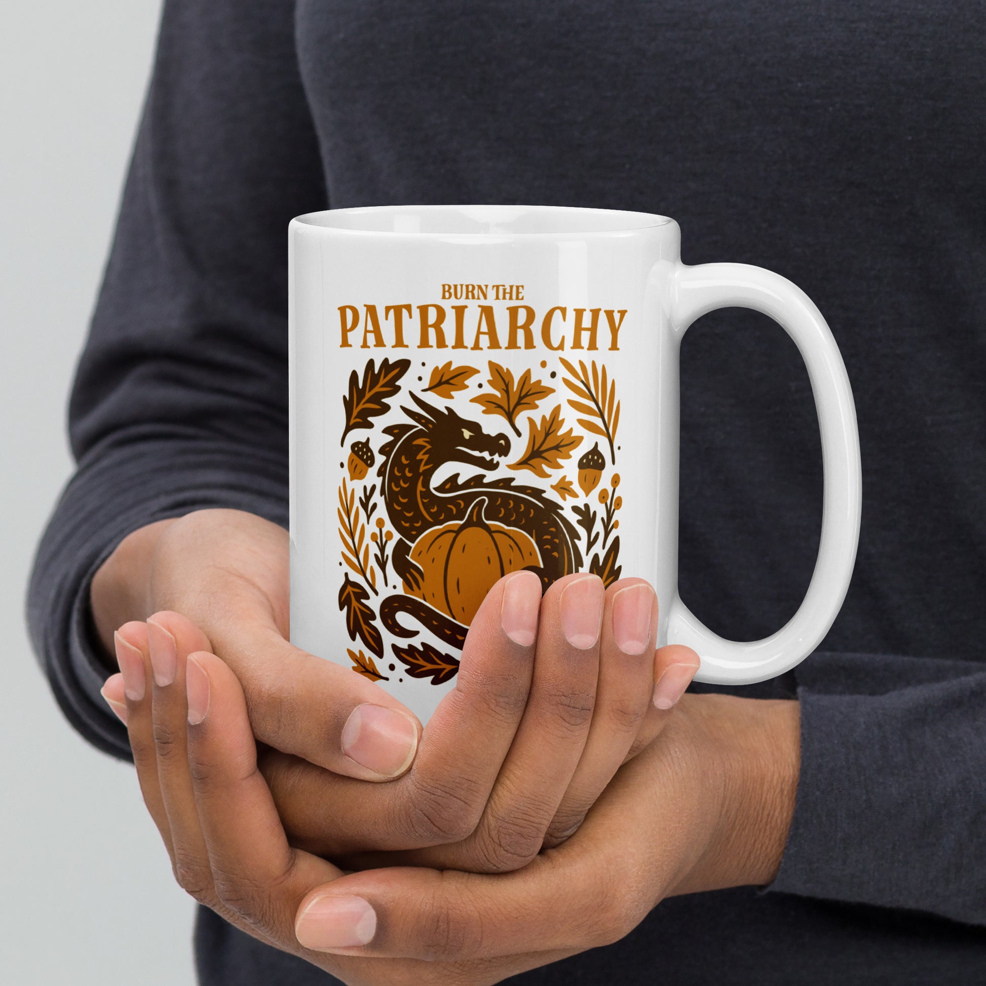 Activist mug with dragon coiled around pumpkin and leaves, “Burn the Patriarchy” feminist autumn coffee cup design.