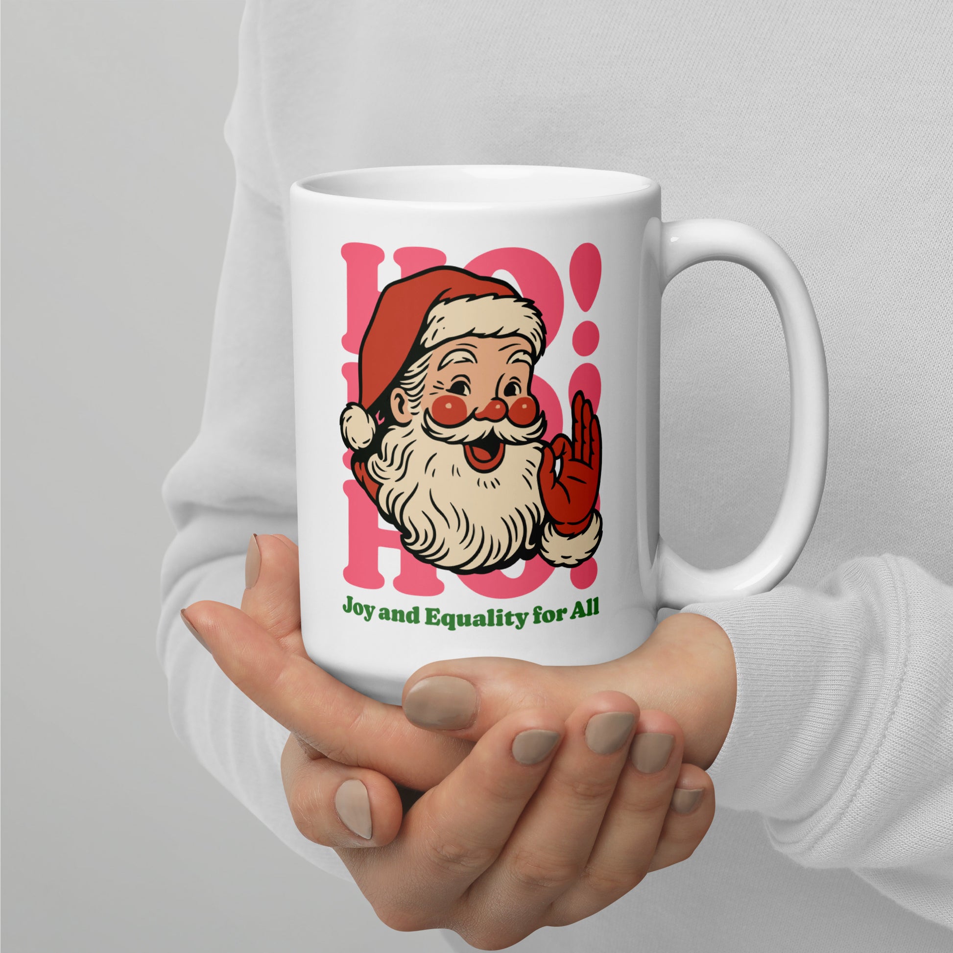 Side view of the 15 oz white ceramic mug being held with both hands, featuring the retro Santa illustration and the phrase “Joy and Equality for All,” printed by Blue Wave USA.