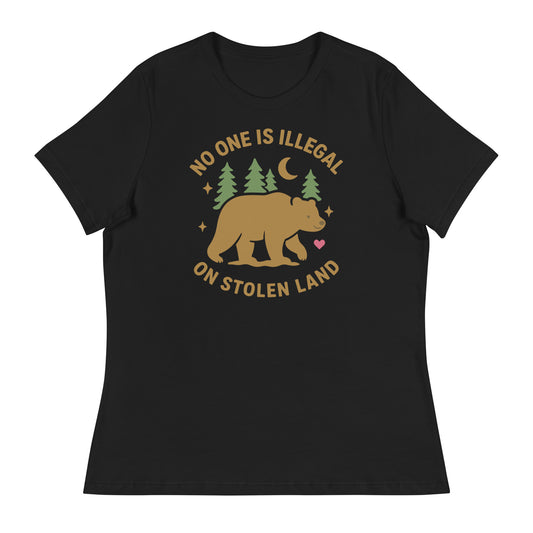 Black women’s relaxed t-shirt featuring a tan bear, pine trees, moon, stars, and the message “NO ONE IS ILLEGAL ON STOLEN LAND,” printed in warm earthy tones.