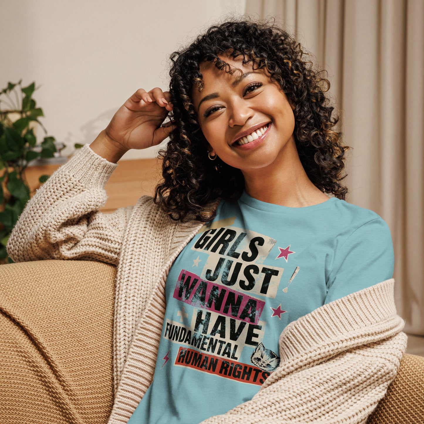 Model lounging in a heather blue “Girls Just Wanna Have Fundamental Human Rights” t-shirt with pink and cream collage-style print. Feminist lifestyle design by Blue Wave USA.
