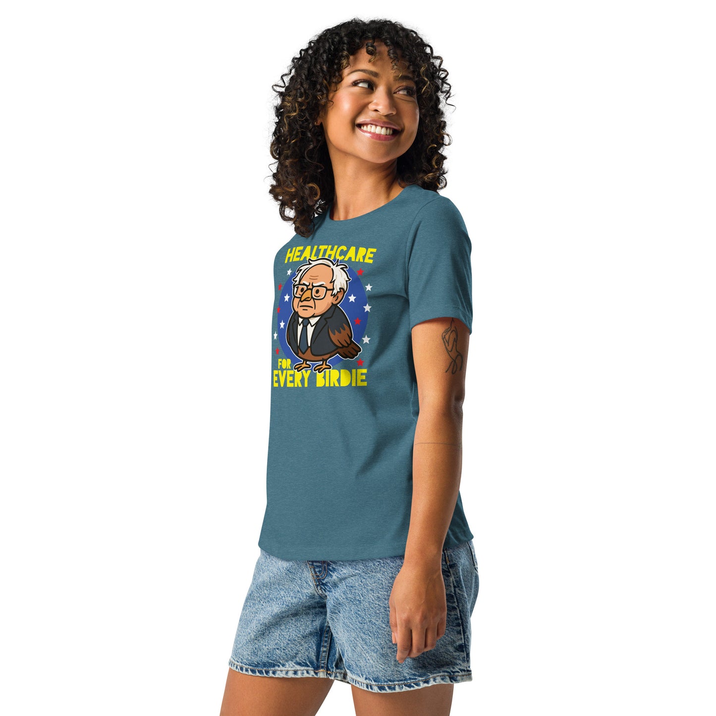 Person wearing a blue women’s relaxed t-shirt showcasing the “Healthcare for Every Birdie” cartoon owl design with bold, colorful political artwork.