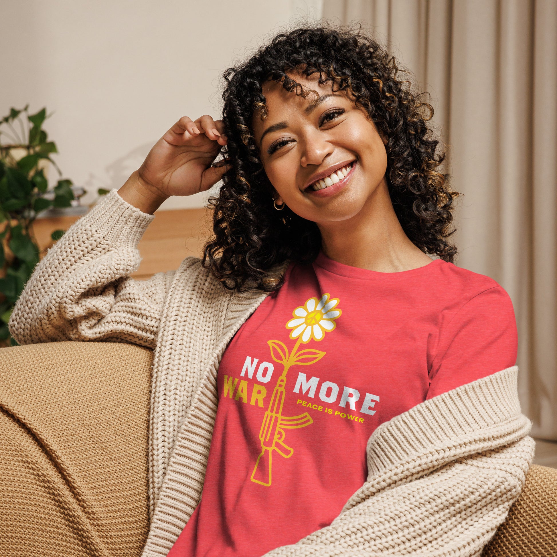 Model wearing heather red women’s relaxed t-shirt featuring yellow flower rising from rifle design and concise anti-war message across front.