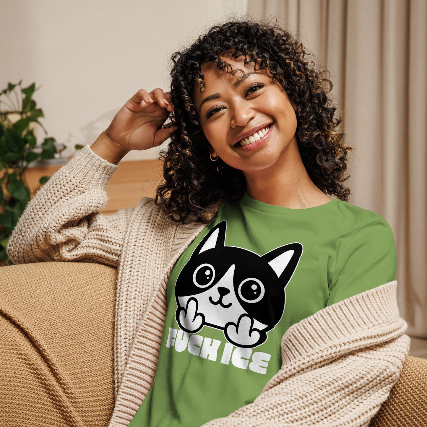Model wearing leaf green women’s relaxed t-shirt featuring bold graphic cartoon cat flipping the middle finger, clean white illustration, printed message “FUCK ICE,” progressive graphic tee from Blue Wave USA.
