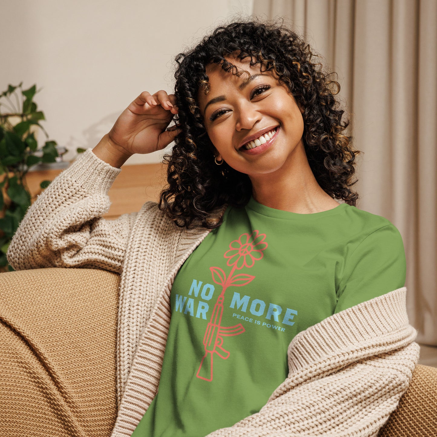 Model wearing leaf green women’s relaxed t-shirt featuring flower-and-rifle graphic and “NO MORE WAR” text, everyday progressive apparel statement.
