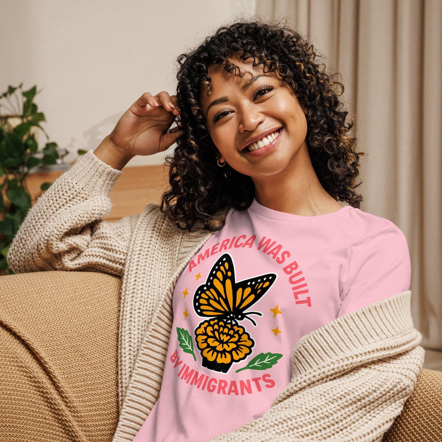 Smiling woman in pink “America Was Built by Immigrants” relaxed fit T-shirt, activist tee celebrating diversity and inclusion.