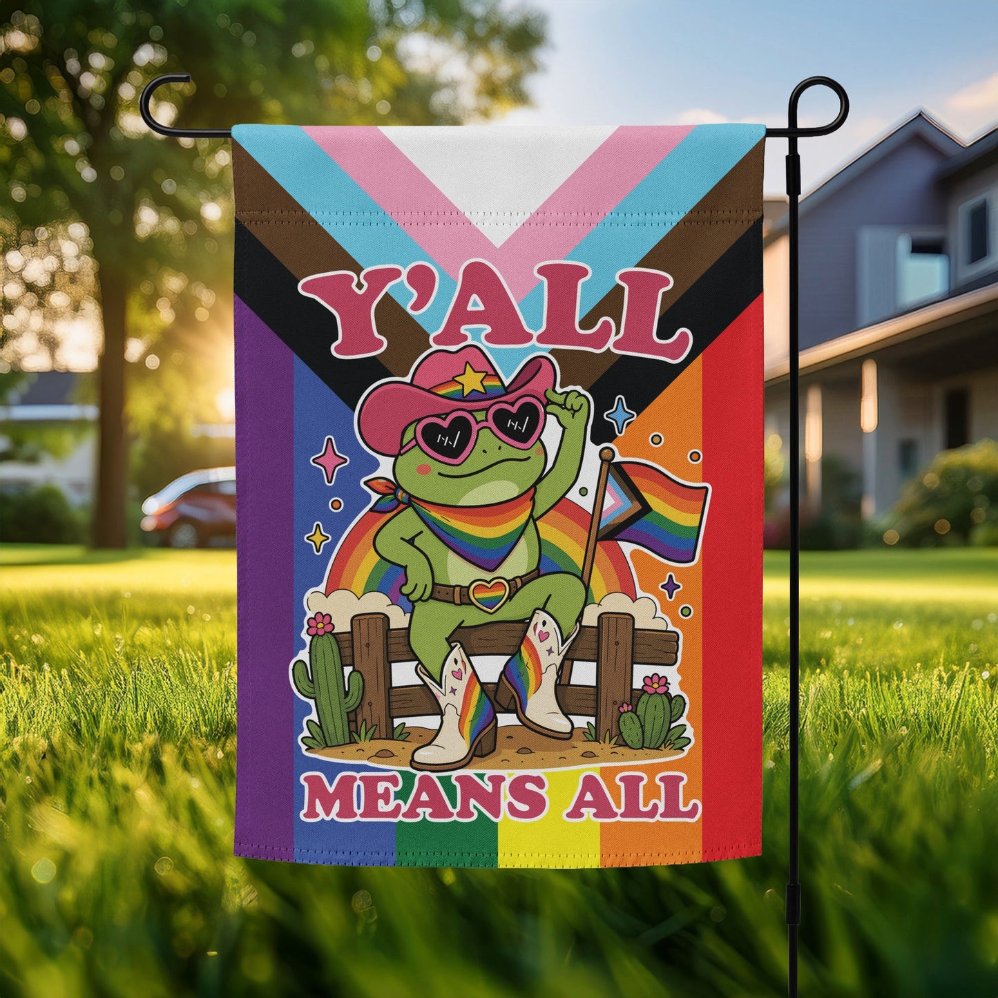 Garden flag featuring a rainbow cowboy frog in heart-shaped sunglasses holding a pride flag against a colorful Pride-inspired background with bold “Y’All Means All” message.